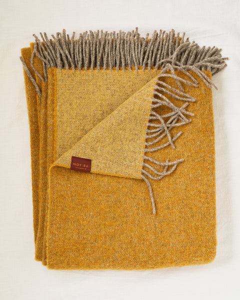 Mustard yellow throw blanket with gray fringe on a white background