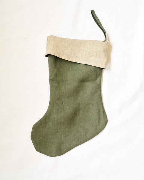Green Christmas stocking with beige trim on a white background